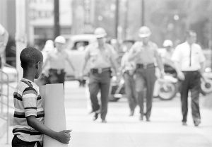 Deputies approach child demonstrator in front of the Dallas County courthouse in Selma, Alabama, July 8, 1964. Photography by Matt Herron.